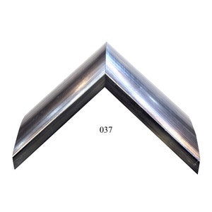 May include: A corner section of a picture frame with a metallic silver and dark grey brushed finish. The frame profile has a curved, rounded shape and features the number 037 printed in black text near the inner corner of the frame sample.