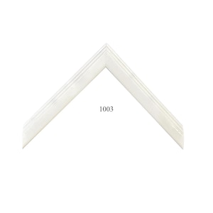 May include: A white picture frame corner sample with a smooth, glossy finish and a stepped, tiered profile. The frame features a clean, angular design with a pointed top edge. The number 1003 is printed in black text on the white surface.