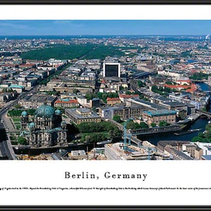 May include: An aerial view of Berlin, Germany, showing a cityscape with buildings, streets, and a river. The photo includes the Berlin Cathedral and the Brandenburg Gate.