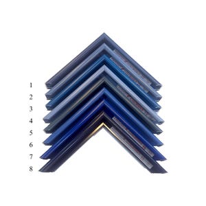 May include: A collection of eight picture frame samples in various shades of blue, arranged in a layered, angled display. Each frame corner is labeled with a number from 1 to 8, and some have text labels.