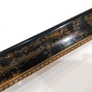 May include: A black picture frame with a gold trim and a decorative pattern of gold dots along the edge.