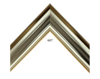 May include: A close-up of a corner of a silver and gold picture frame. The frame has a raised, ornate design. The number 607 is printed on the frame.
