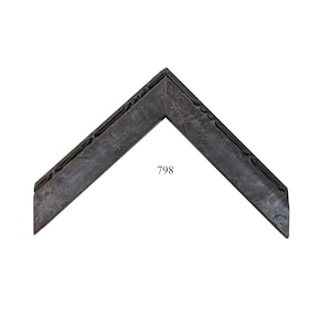 May include: An L-shaped corner section of a picture frame featuring a dark charcoal gray finish with a mottled, textured surface pattern and a raised, decorative inner edge detail. The number 798 is printed in black in the center of the frame.