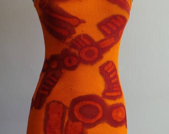Puede incluir: Camiseta de tirantes naranja con un diseño abstracto marrón. La camiseta está hecha de tejido de canalé.