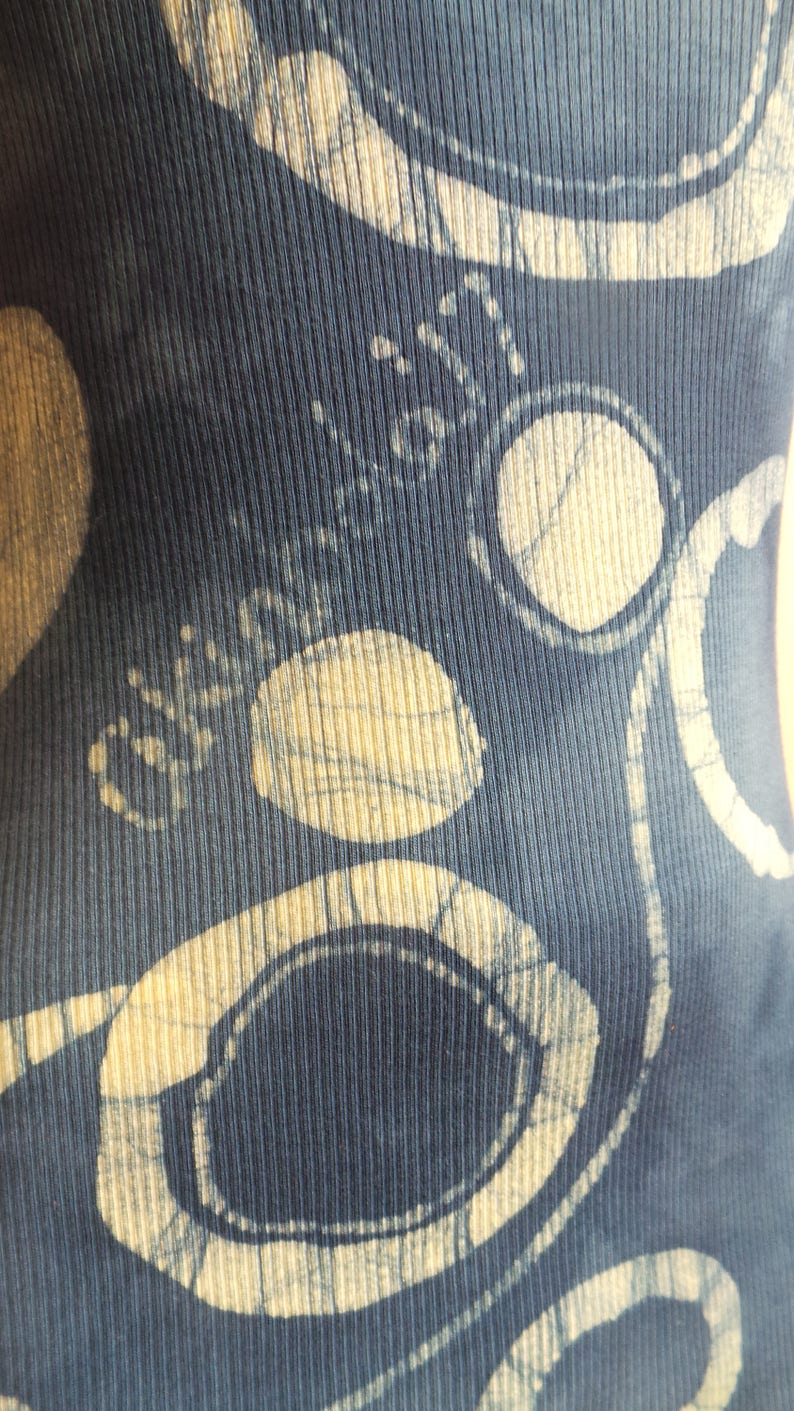 Puede incluir: Tela azul con un dise&ntilde;o estampado blanco y azul claro. El patr&oacute;n presenta c&iacute;rculos y espirales.