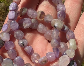 Bracciale elastico con perline di charoite russa viola naturale, forma burattata, adatto a taglie L/XL. Gioiello energetico curativo, accessorio o regalo.