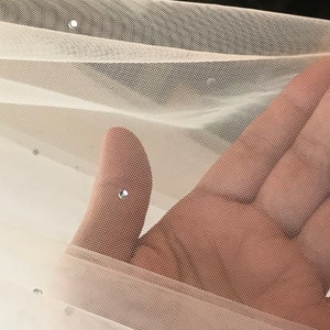May include: White tulle fabric with small, clear rhinestones scattered throughout. The fabric is soft and sheer, with a delicate texture.