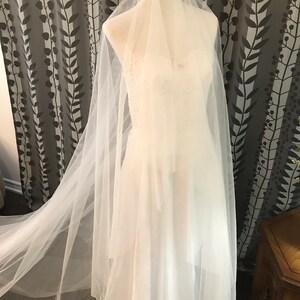 Op de afbeelding: Een witte tule bruids sluier met een lange sleep, getoond op een mannequin.