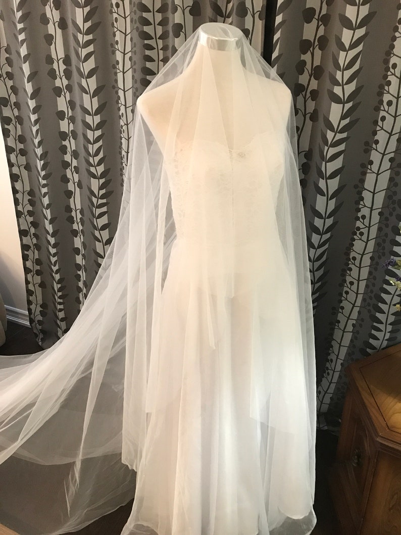 Op de afbeelding: Een witte tule bruids sluier met een lange sleep, getoond op een mannequin.