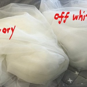 Op de afbeelding: Twee stukken doorschijnend stof, een met het label "ivoor" en de andere met het label "off white".