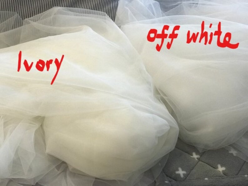 Op de afbeelding: Twee stukken doorschijnend stof, een met het label "ivoor" en de andere met het label "off white".