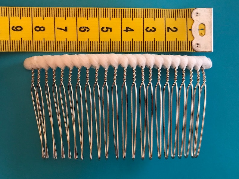 May include: A silver hair comb with white, rounded teeth. The comb is about 2 inches long.