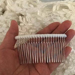 May include: A white comb with a white, twisted wire base. The comb has a silver metal base and a row of silver teeth.