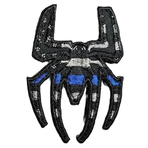 May include: Black and blue embroidered patch of a spider with a thin blue line across the middle of the body.