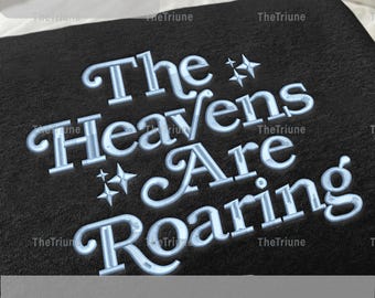 Peut inclure: Tissu noir avec la phrase brodée "The Heavens Are Roaring" en bleu clair. Le motif comprend des étoiles décoratives. Le coin supérieur gauche affiche les options de taille : 12.7cm, 15.2cm, 17.8cm et 20.3cm.