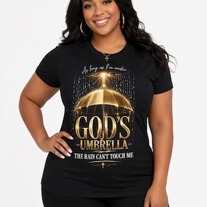 May include: Black t-shirt with a gold umbrella graphic and the text "GOD'S UMBRELLA THE RAIN CAN'T TOUCH ME." The design includes a cross and the phrase "As long as I'm under."