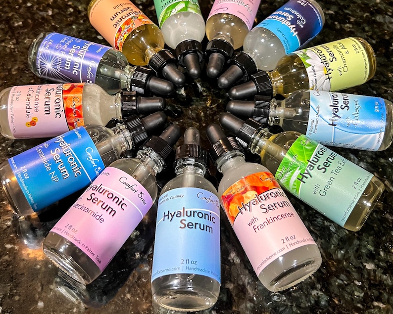May include: A circular arrangement of twelve clear glass dropper bottles containing Hyaluronic Serum. Each bottle features a black dropper cap and a label with specific ingredients like Niacinamide, Frankincense, Collagen, and Calendula, each holding 2 fl oz.