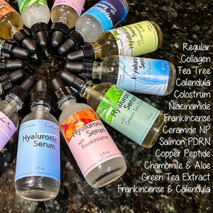May include: A collection of clear glass dropper bottles containing Hyaluronic Serum with various labels including Collagen, Tea Tree, Calendula, Colostrum, Niacinamide, Frankincense, Ceramide NP, Salmon PDRN, Chamomile & Aloe, and Green Tea Extract.