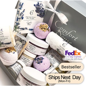 May include: A gray gift box filled with lavender-scented bath products, including bath bombs, bath salts, body butter, soap, and a loofah. The box is decorated with a white ribbon and a tag that says "Comfort Sense".