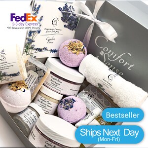 May include: A gray gift box filled with lavender-scented bath products, including bath bombs, bath salts, body butter, soap, and a loofah. The box also includes a white face towel. The box is labeled "Comfort Sense" and "Bestseller".