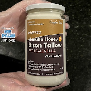 May include: A glass jar with a white lid, filled with a creamy, off-white substance. The label reads "Whipped Manuka Honey Bison Tallow with Calendula Vanilla Bean." The jar is 24 oz. and includes the text "All Natural Premium Quality" and "Comfort Sense."