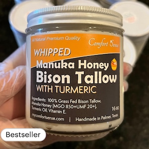 May include: A white jar with a black label that reads "Whipped Manuka Honey Bison Tallow with Turmeric". The jar is labeled "All Natural Premium Quality Comfort Sense" and contains 16 oz of product. The jar is labeled "Bestseller".