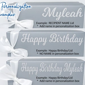 May include: Three grey gift boxes with white ribbon and bow closures. The lids feature examples of personalisation, including the name "Myleah" and the phrase "Happy Birthday." Text on the boxes provides instructions for personalisation.
