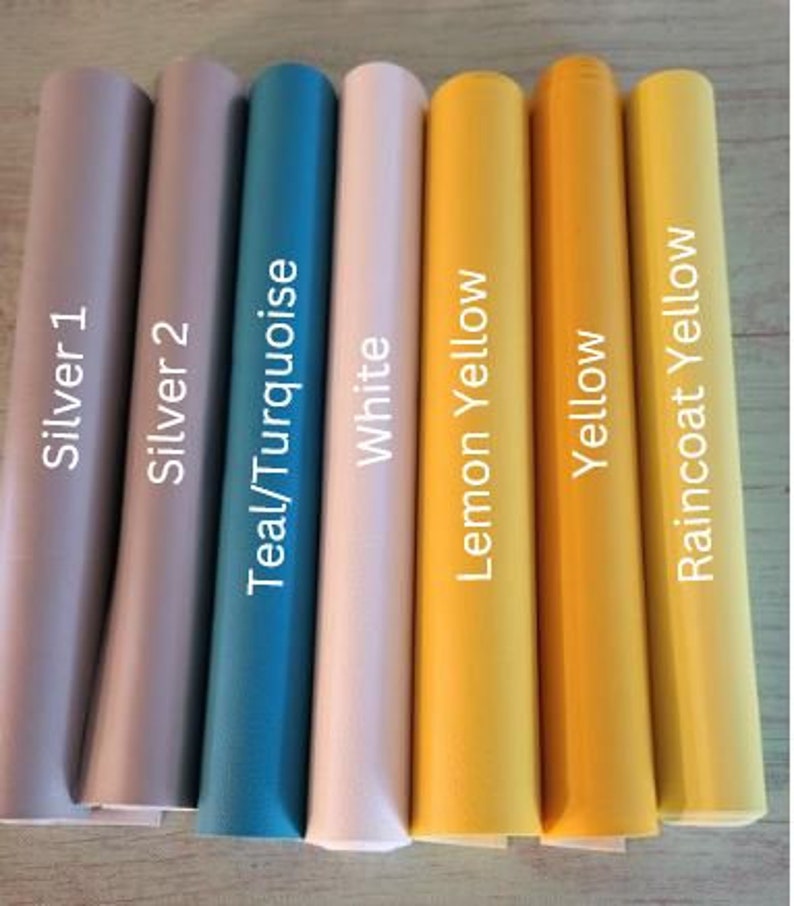 Op de afbeelding: Acht rollen vinyl plakband in verschillende kleuren, waaronder zilver, teal, wit, citroengeel, geel en regenjasgeel. De rollen zijn gelabeld met hun respectievelijke kleuren.