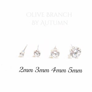 May include: Four clear, round stud earrings of varying sizes are displayed against a white background. The sizes are 2mm, 3mm, 4mm, and 5mm. The text "OLIVE BRANCH BY AUTUMN" is at the top of the image.