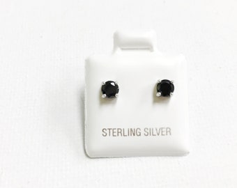 May include: A pair of sterling silver stud earrings with black round gemstones.