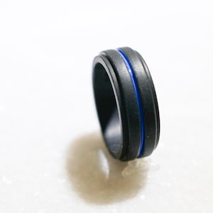 May include: A black silicone ring with a thin blue line around the center.