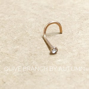 May include: A gold nose ring with a small clear gemstone.