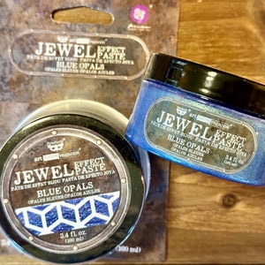 May include: Two jars of "Jewel Effect Paste" in "Blue Opals" color. The jars have black lids and labels with text in multiple languages. Each jar contains 3.4 fl oz (100 ml) of paste. The packaging is on a wooden surface.