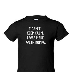 May include: Black t-shirt with white text that reads "I can't keep calm, I was made with Kompa."