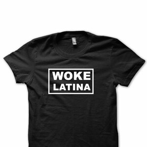 May include: Black t-shirt with white text that reads "WOKE LATINA" in a rectangle.