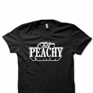May include: Black t-shirt with white text that reads "Just Peachy".