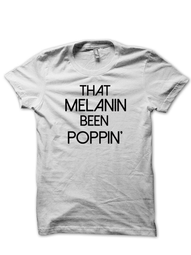 May include: White t-shirt with black text that reads "THAT MELANIN BEEN POPPIN'"