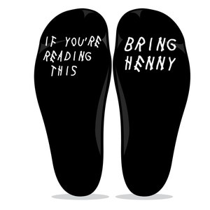 May include: A pair of black socks with white text. One sock says "If you're reading this" and the other sock says "Bring Henny".