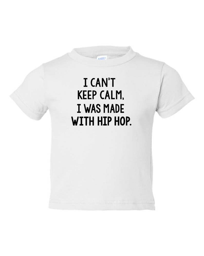 Op de afbeelding: Wit baby t-shirt met zwarte tekst die "Ik kan niet rustig blijven. Ik ben gemaakt met hiphop." zegt.