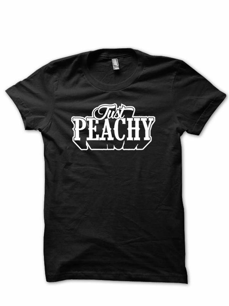 May include: Black t-shirt with white text that reads "Just Peachy".