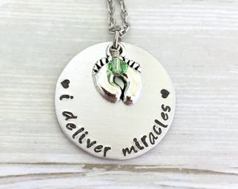 May include: Silver necklace with a round pendant that says "I deliver miracles" with a small charm of baby footprints and a green crystal.