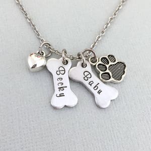 May include: Silver necklace with a heart charm, two bone charms engraved with the names "Becky" and "Babu", and a paw print charm.