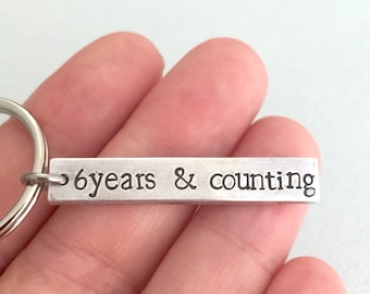 May include: Silver keychain with a rectangular tag that reads "6 years & counting".