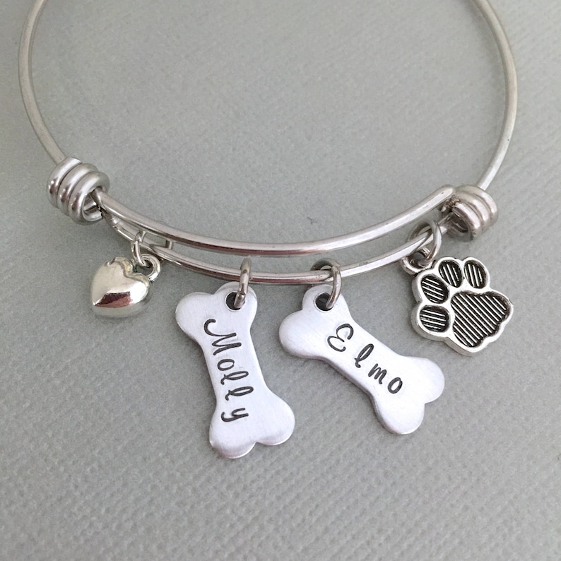May include: Silver charm bracelet with a heart, paw print, and two bone charms engraved with the names "Molly" and "Elmo".