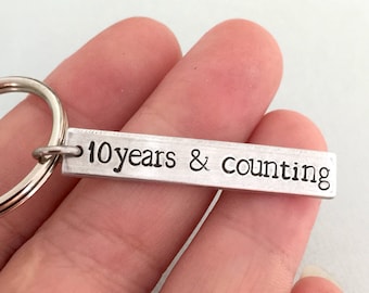 May include: Silver keychain with a rectangular tag that reads "10 years & counting".