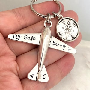 Op de afbeelding: Zilveren vliegtuig sleutelhanger met de woorden "Fly Safe" en "Benny" erop gegraveerd. De sleutelhanger bevat ook een kompas bedel.