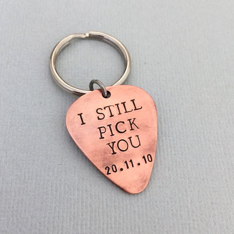 May include: Copper guitar pick keychain with the text "I still pick you 20.11.10" engraved on it.