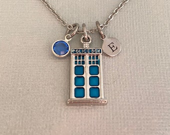 May include: A silver necklace with a blue crystal charm, a silver charm with the text "POLICE BOX" and a silver charm with the letter "E".