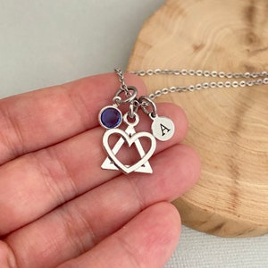 Puede incluir: Collar de plata con un dije de corazón, un pequeño dije de piedra preciosa azul y un dije con la letra 'A'.