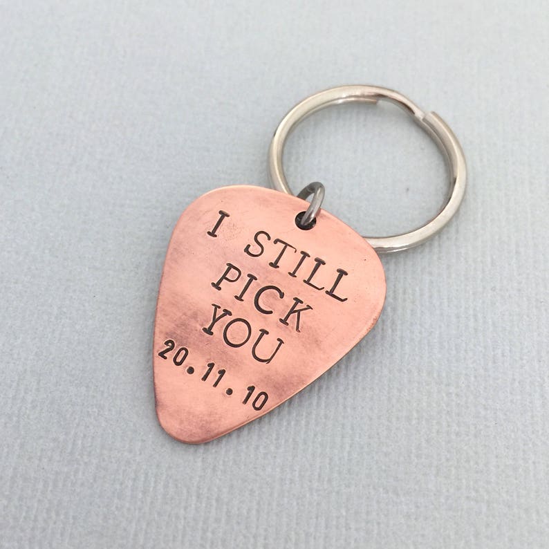 May include: Copper guitar pick keychain with the text "I Still Pick You" and the date "20.11.10" engraved on it.